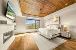 Experience luxury mountain living in this stunning bedroom, featuring a cozy fireplace and a large window with breathtaking views.