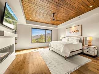 Experience luxury mountain living in this stunning bedroom, featuring a cozy fireplace and a large window with breathtaking views.