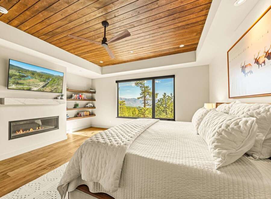 Experience luxury mountain living in this stunning bedroom featuring a modern gas fireplace and a wall-mounted TV for ultimate relaxation.