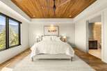 Experience luxury mountain living in this stunning bedroom featuring a warm wood-paneled ceiling and a large window with breathtaking views.