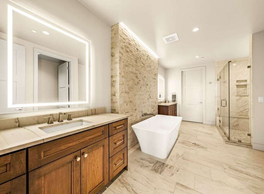 Experience luxury in this stunning master bathroom, featuring a freestanding soaking tub and a spacious glass-enclosed shower with marble tile.