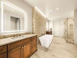 Experience luxury in this stunning master bathroom, featuring a freestanding soaking tub and a spacious glass-enclosed shower with marble tile.