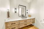 This modern bathroom features a sleek vanity with natural wood drawers and a white marble countertop.