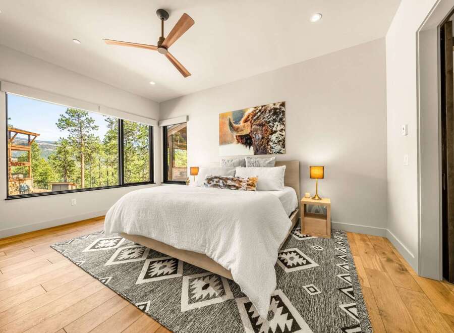 Experience luxury mountain living in this stunning bedroom featuring a king-sized bed adorned with plush white linens and a striking bison artwork above.