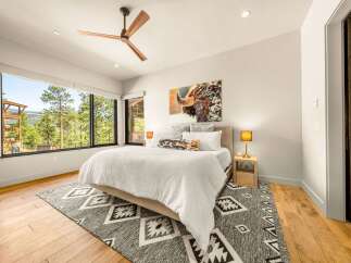Experience luxury mountain living in this stunning bedroom featuring a king-sized bed adorned with plush white linens and a striking bison artwork above.