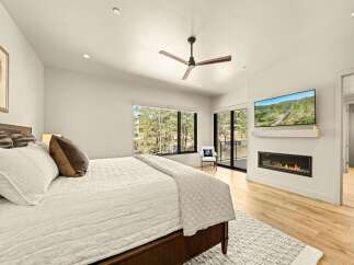 Experience luxury and comfort in this stunning bedroom, featuring a modern gas fireplace and a wall-mounted TV for ultimate relaxation.