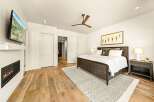 Experience luxury and comfort in this master bedroom, featuring a modern gas fireplace and a wall-mounted TV for ultimate relaxation.