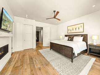 Experience luxury and comfort in this master bedroom, featuring a modern gas fireplace and a wall-mounted TV for ultimate relaxation.