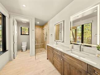 Experience luxury in this modern bathroom featuring a spacious walk-in shower with elegant tilework and a built-in bench.