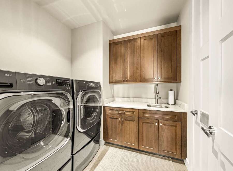 This laundry room boasts a modern and functional design, featuring a stacked LG ThinQ washer and dryer set for efficient space utilization.