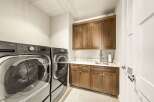 This laundry room boasts a modern and functional design, featuring a stacked LG ThinQ washer and dryer set for efficient space utilization.