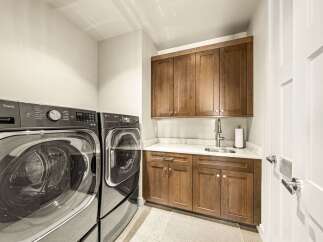 This laundry room boasts a modern and functional design, featuring a stacked LG ThinQ washer and dryer set for efficient space utilization.