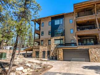 Experience luxury mountain living in this stunning multi-level residence, featuring a modern facade with stone accents and expansive balconies perfect for enjoying the surrounding pine forest.