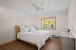 Experience comfort and style in this inviting bedroom, featuring a plush queen-size bed adorned with crisp white linens and an abundance of pillows.