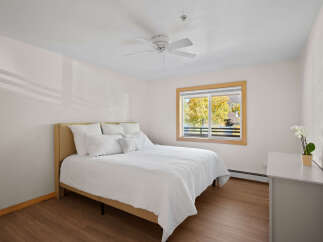 Experience comfort and style in this inviting bedroom, featuring a plush queen-size bed adorned with crisp white linens and an abundance of pillows.