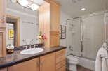 This bright and airy bathroom features a spacious vanity with ample storage and a granite countertop, complemented by a large mirror and elegant light fixtures.