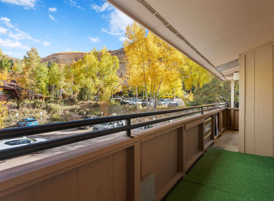 Experience the vibrant beauty of autumn from this charming balcony, offering stunning views of golden aspen trees and rolling hills.