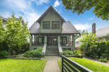 Charming duplex home featuring a classic architectural style with stone accents and a welcoming covered porch.
