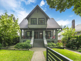 Charming duplex home featuring a classic architectural style with stone accents and a welcoming covered porch.