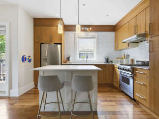 Experience modern living in this stunning kitchen, featuring sleek, warm wood cabinetry and a spacious island perfect for casual dining or entertaining.