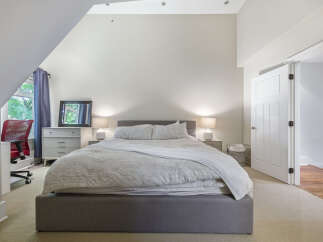 Discover this inviting bedroom featuring a comfortable king-sized bed with a soft, textured duvet and a cozy throw blanket.