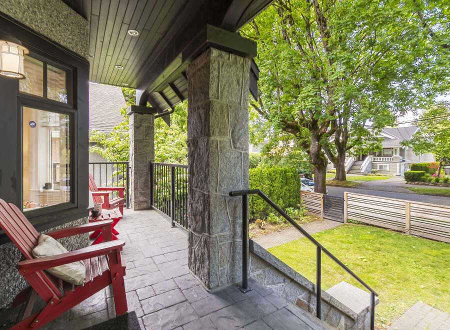 Enjoy relaxing evenings on this charming covered porch, complete with comfortable red Adirondack chairs and a stone-clad pillar.
