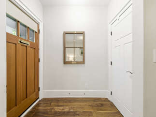 Step into this inviting entryway featuring a warm wooden door with a classic mail slot and a stylish roller shade.