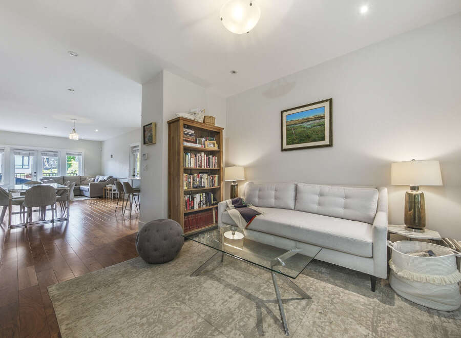 Step into this inviting living space featuring a plush white sofa complemented by a modern glass coffee table and a cozy area rug.