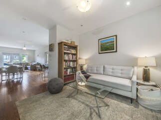 Step into this inviting living space featuring a plush white sofa complemented by a modern glass coffee table and a cozy area rug.