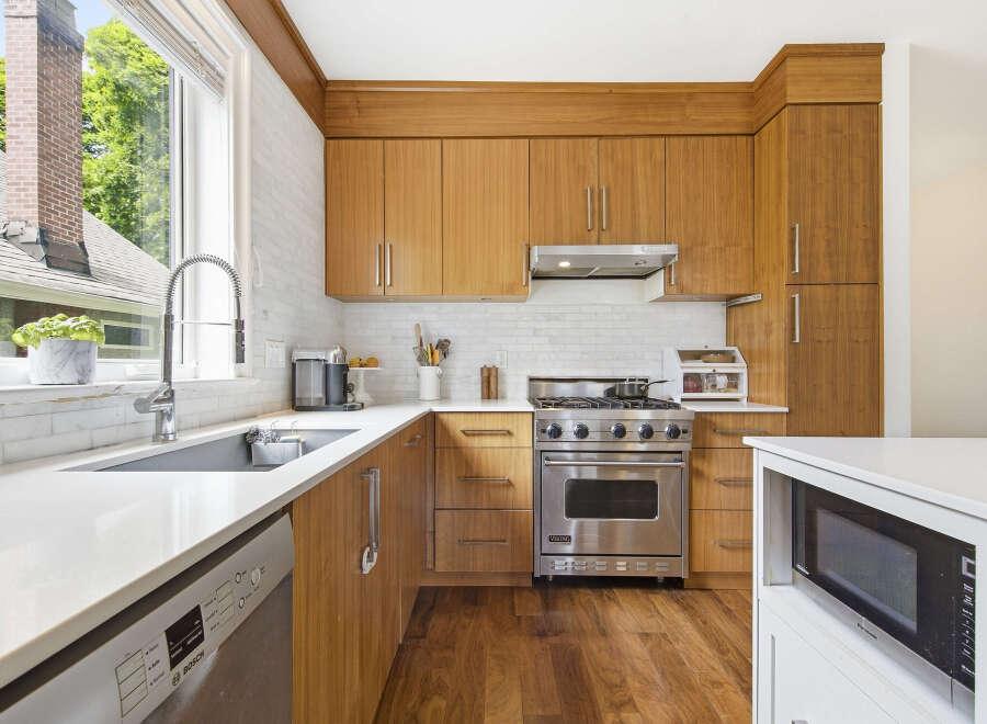 This modern kitchen boasts sleek, warm wood cabinetry complemented by a white subway tile backsplash and durable quartz countertops.