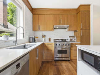 This modern kitchen boasts sleek, warm wood cabinetry complemented by a white subway tile backsplash and durable quartz countertops.