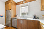 This modern kitchen features sleek, warm wood cabinetry complemented by a white subway tile backsplash.