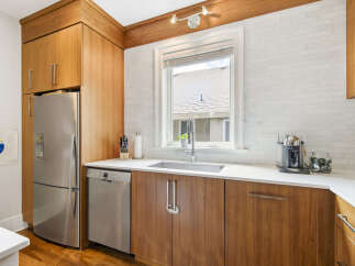 This modern kitchen features sleek, warm wood cabinetry complemented by a white subway tile backsplash.