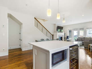 This modern open-concept living space features a sleek white kitchen island with integrated microwave and wine cooler, perfect for entertaining.