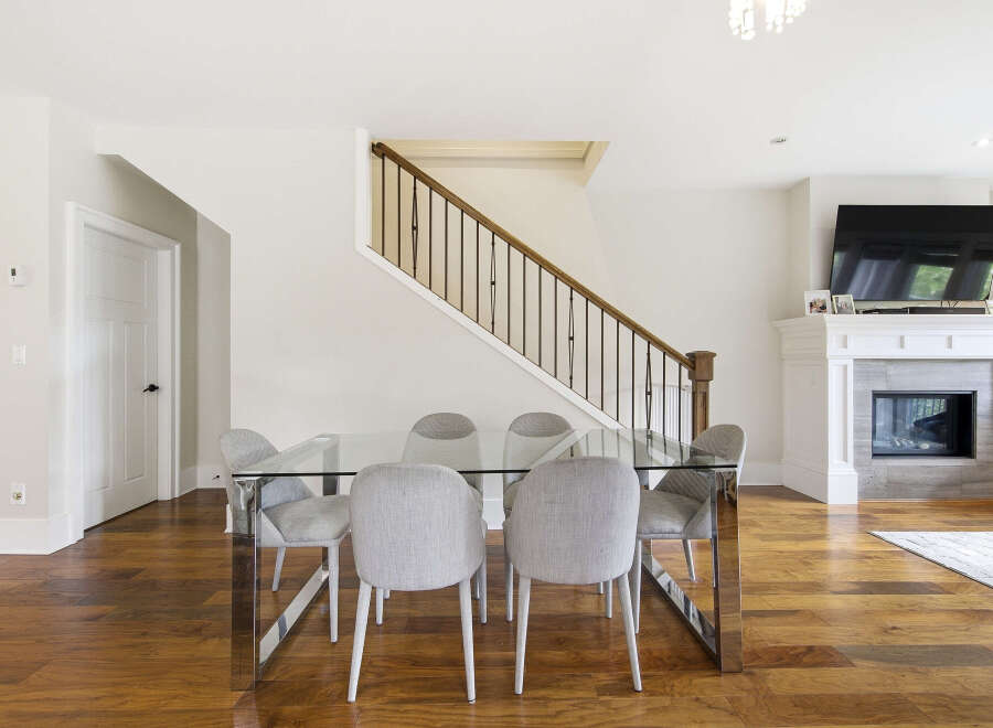 Experience modern elegance in this spacious dining area, featuring a sleek glass-top dining table with chrome legs, complemented by plush upholstered chairs.