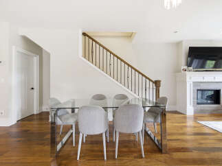 Experience modern elegance in this spacious dining area, featuring a sleek glass-top dining table with chrome legs, complemented by plush upholstered chairs.