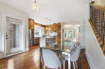 This spacious open-concept dining and kitchen area features a sleek glass-top dining table with comfortable upholstered chairs, perfect for family gatherings.