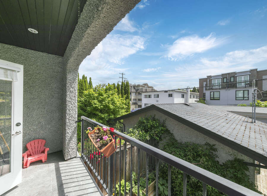 Enjoy the outdoors from this charming balcony, complete with a vibrant red Adirondack chair and a flower box brimming with colorful blooms.