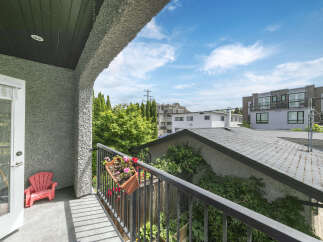 Enjoy the outdoors from this charming balcony, complete with a vibrant red Adirondack chair and a flower box brimming with colorful blooms.
