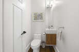 This modern powder room features a sleek white toilet and a floating vanity with a wood grain finish.