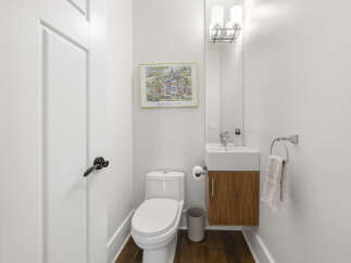 This modern powder room features a sleek white toilet and a floating vanity with a wood grain finish.