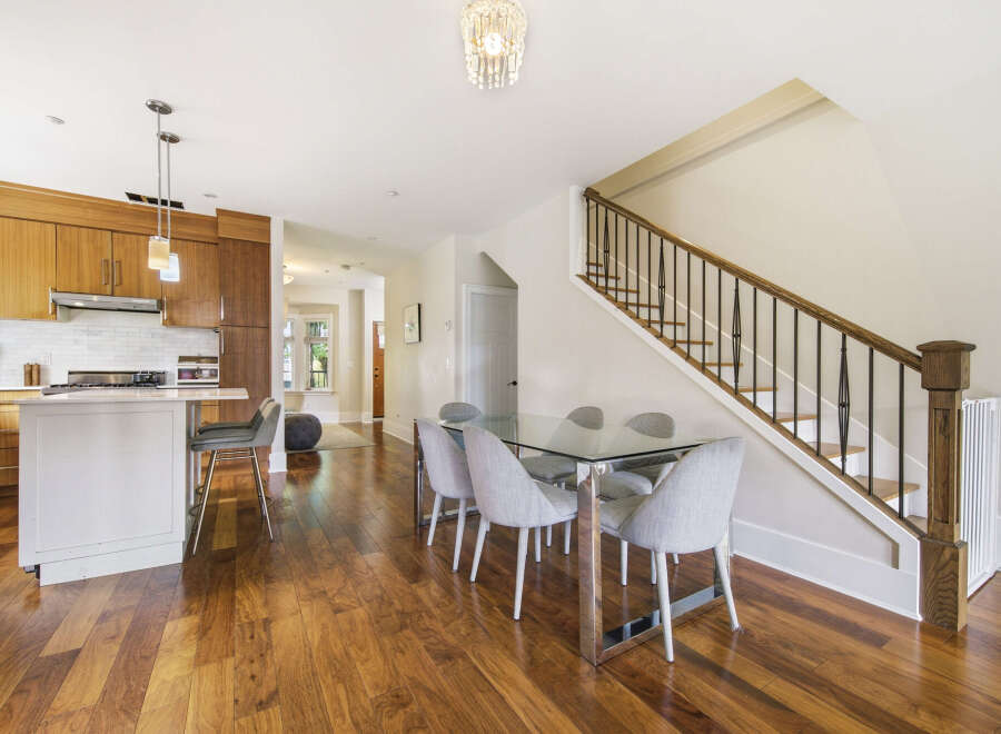 Experience modern living in this beautifully appointed kitchen and dining area, featuring sleek wooden cabinetry and a stylish glass-top dining table perfect for entertaining.