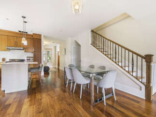 Experience modern living in this beautifully appointed kitchen and dining area, featuring sleek wooden cabinetry and a stylish glass-top dining table perfect for entertaining.
