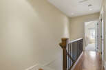 This hallway features a beautiful wooden staircase railing with dark spindles, leading to a bright room with natural light.