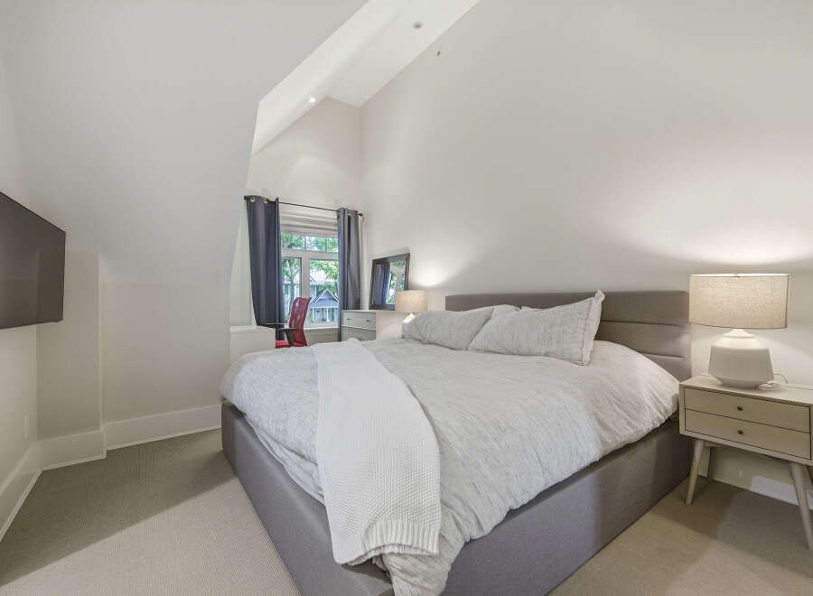 This charming bedroom features a spacious king-size bed with a light grey upholstered headboard, perfect for a restful night's sleep.