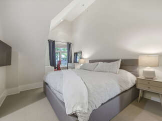 This charming bedroom features a spacious king-size bed with a light grey upholstered headboard, perfect for a restful night's sleep.