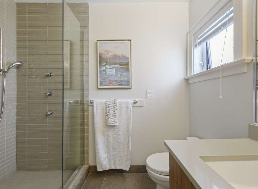 This modern bathroom features a sleek glass-enclosed shower with multiple showerheads and elegant tilework.