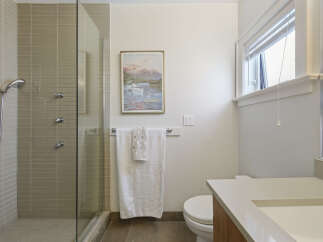 This modern bathroom features a sleek glass-enclosed shower with multiple showerheads and elegant tilework.