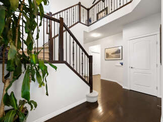 Step into this grand foyer featuring a sweeping staircase with rich dark wood railings and elegant spindles.