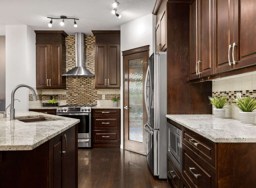 This spacious kitchen boasts dark wood cabinetry, granite countertops, and a sleek stainless steel range with a matching hood.